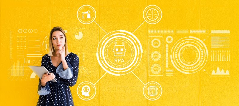 Woman holding a tablet stands before yellow wall with RPA and automation icons, symbolizing AI-enhanced customer interactions.