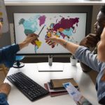 SME team analyzing a world map on a computer screen during a global trade planning session, illustrating cross‑border expansion through platforms like TradeKey.