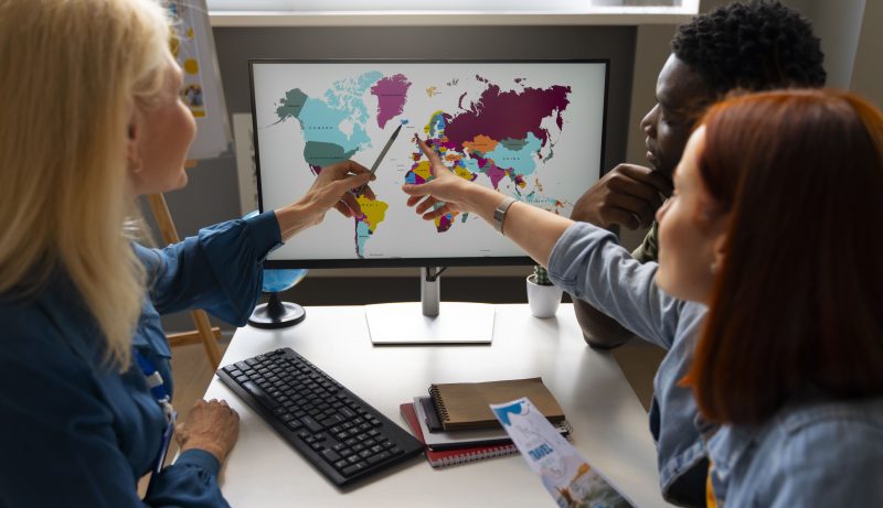 SME team analyzing a world map on a computer screen during a global trade planning session, illustrating cross‑border expansion through platforms like TradeKey.